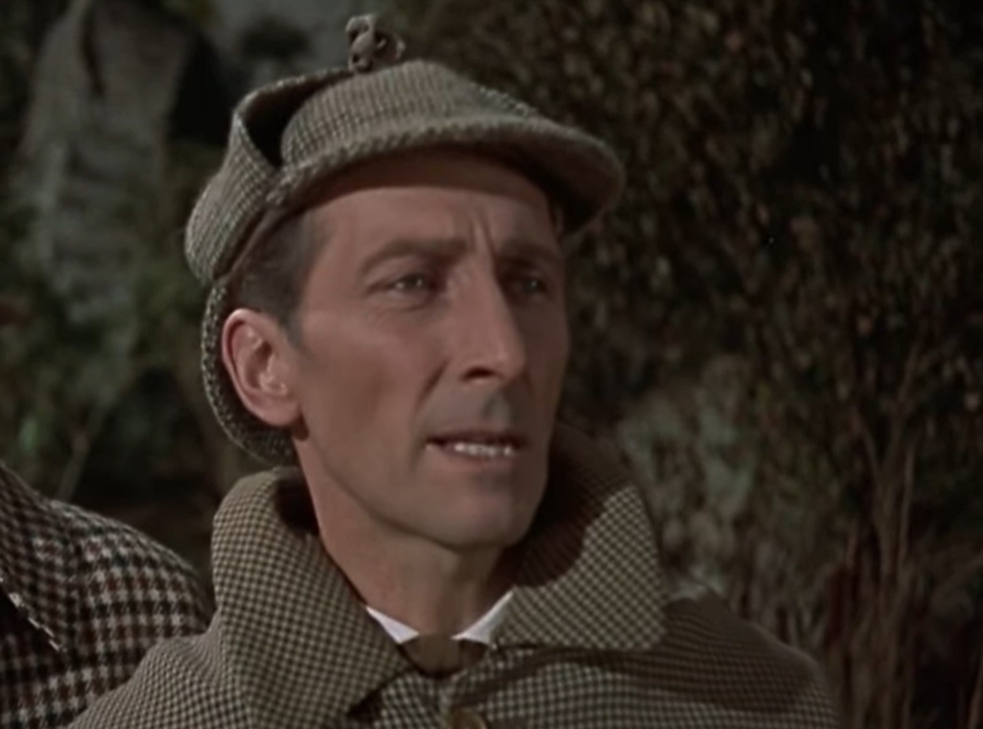Screenshot of Peter Cushing in green coat is looking at side - from The Hound of the Baskervilles (1959)