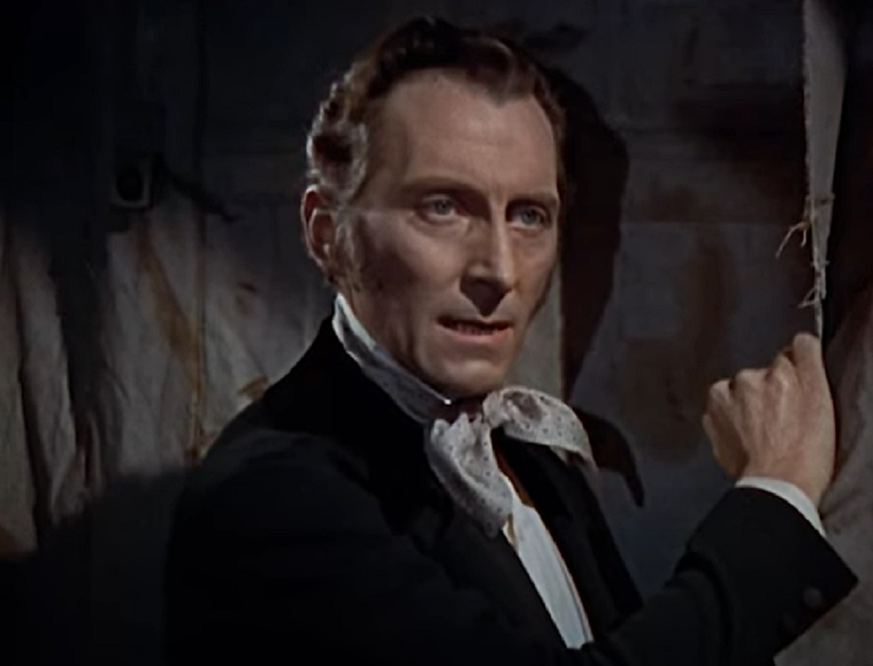 Screenshot of Peter Cushing in black suit is looking at side - from The Revenge Of Frankenstein (1958)