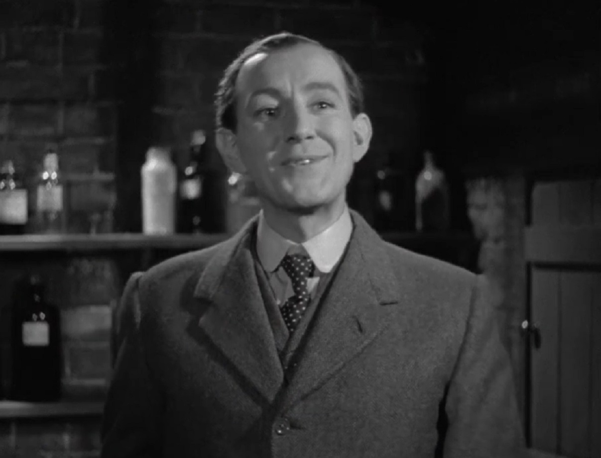 Screenshot of Alec Guinness in suit smiling at camera - from Kind Hearts And Coronets (1949)