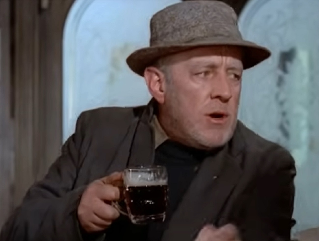 Screenshot of Alec Guinness wearing hat and holding a beer glass - from The Horse's Mouth (1958)