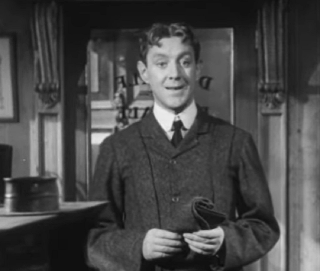 Screenshot of Alec Guinness wearing suit and looking at side - from The Promoter (1952)