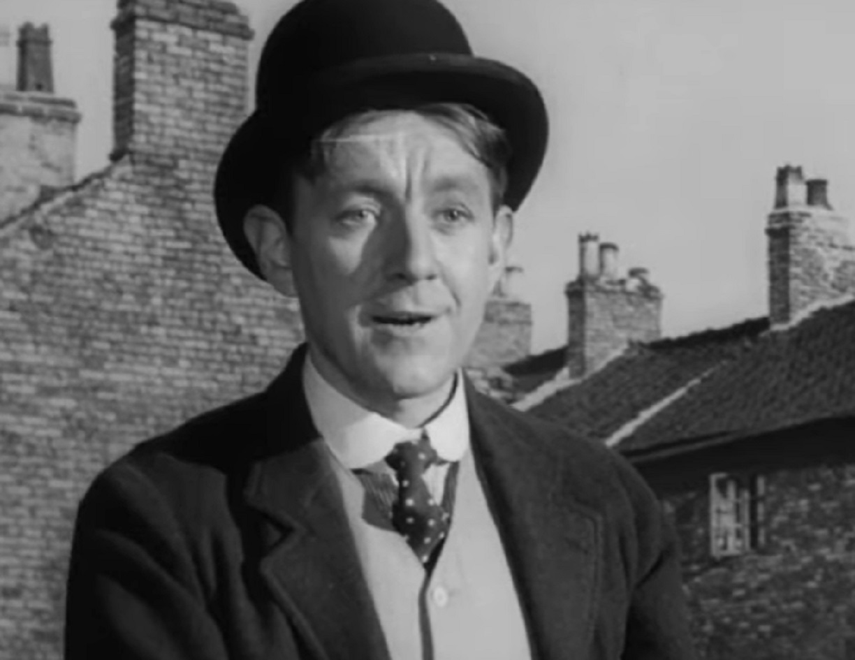 Screenshot of Alec Guinness wearing black hat and suit - from The Promoter (1952)