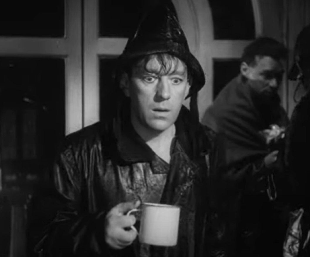 Screenshot of Alec Guinness wearing rain coat and looking scared - from The Promoter (1952)