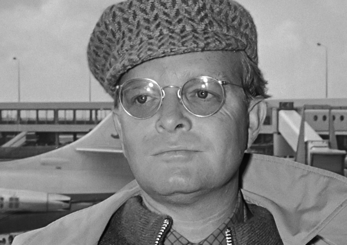 Truman Capote at airport in jacket and hat