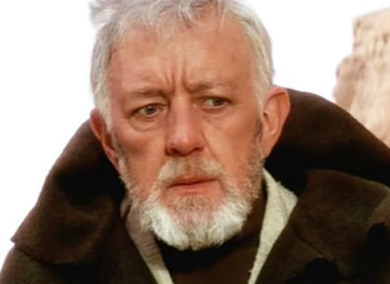 Screenshot of Alec Guinness wearing brown coat and looking down - from Star Wars: Episode IV (1977)