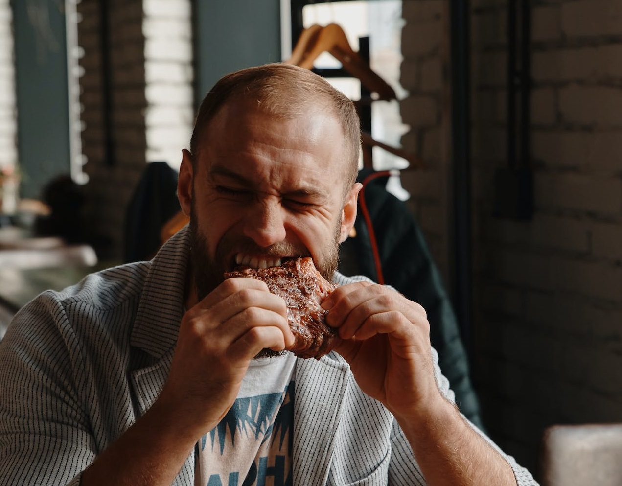 Man eating peace of steak in restaurant.