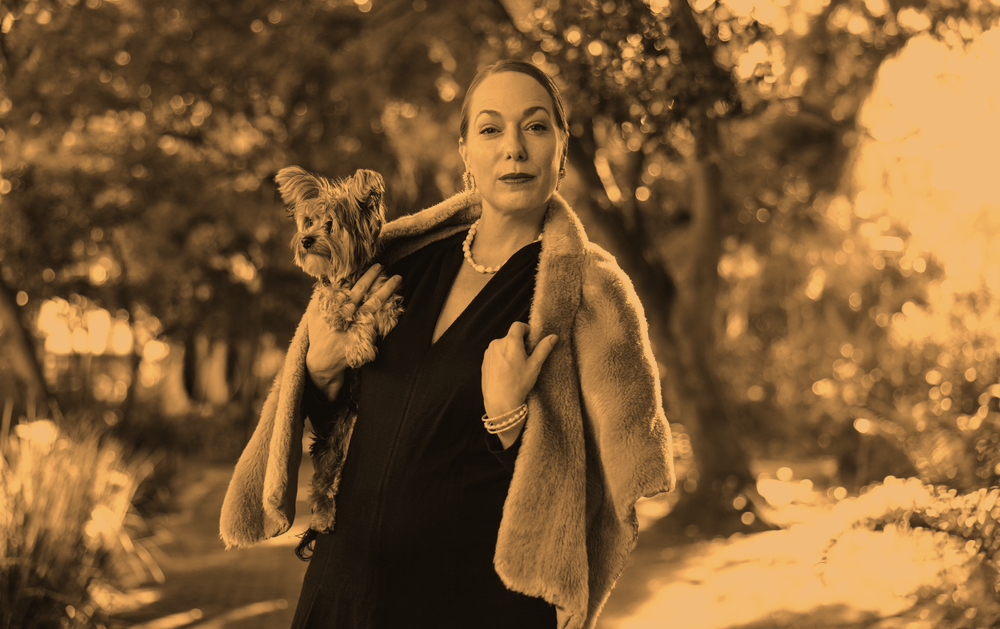 Luxurious woman looking at the camera while holding her puppy outdoors