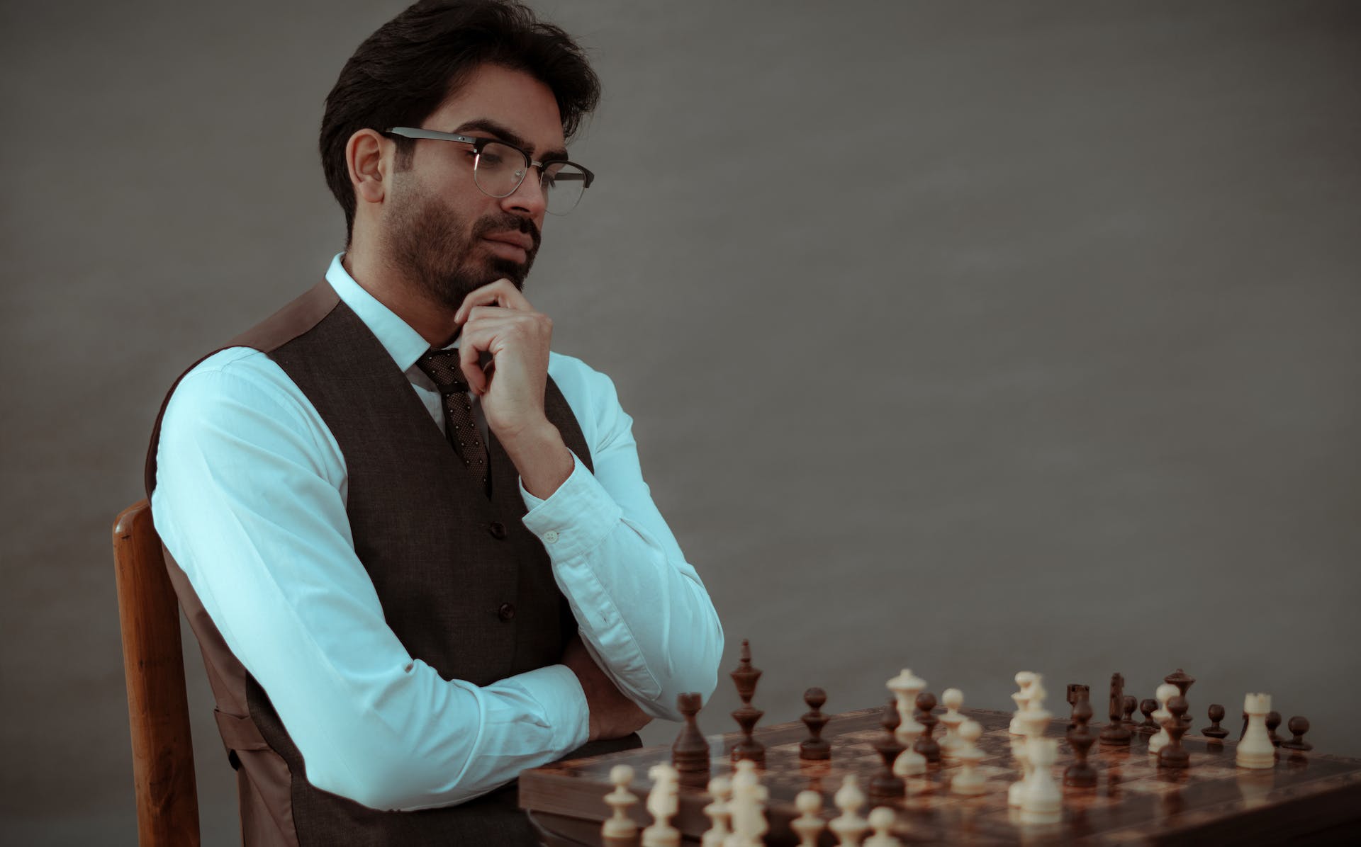 serious man with glasses in a suit thinking over tactic of playing chess
