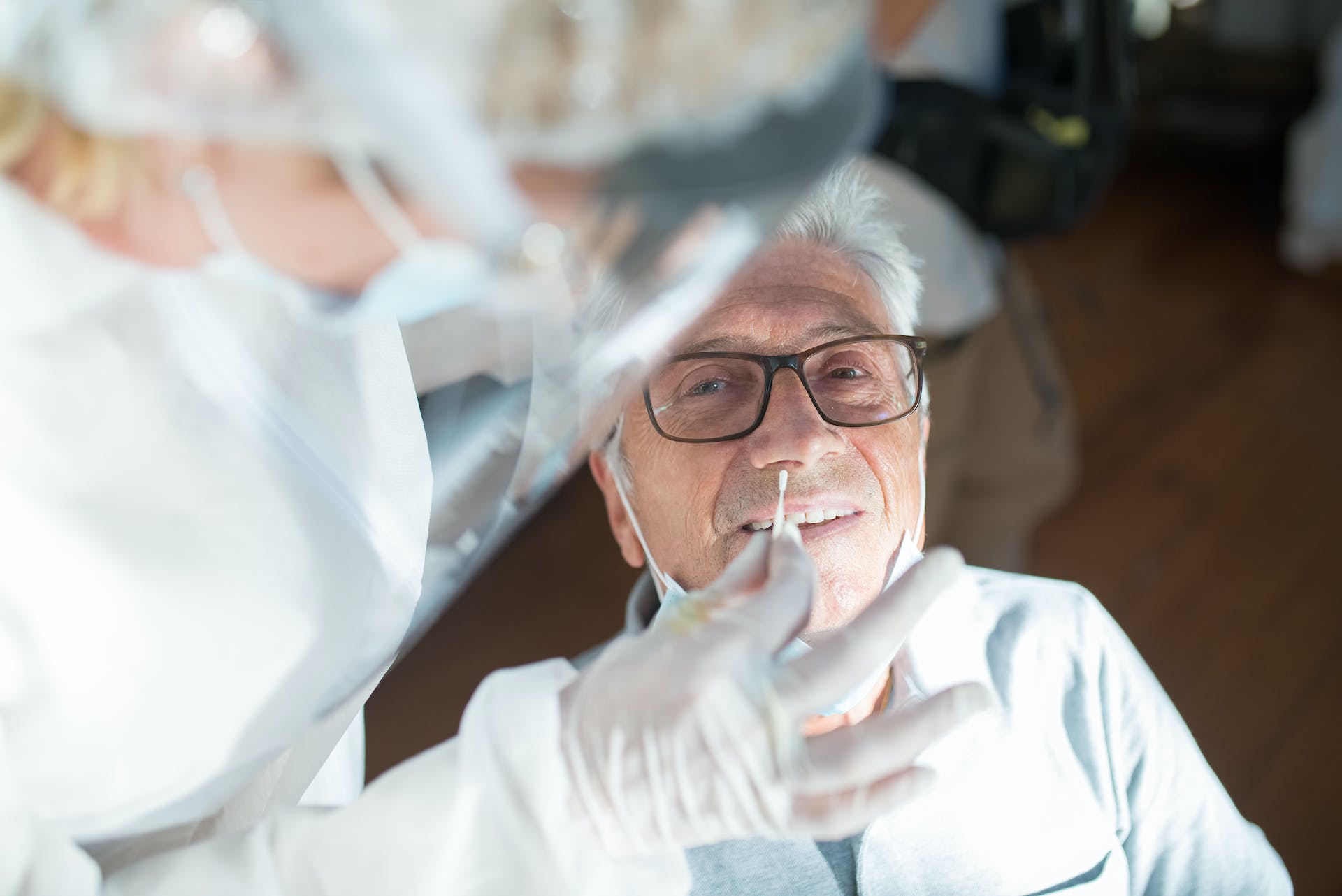 man with glasses getting tested for virus, taking samples from his nose