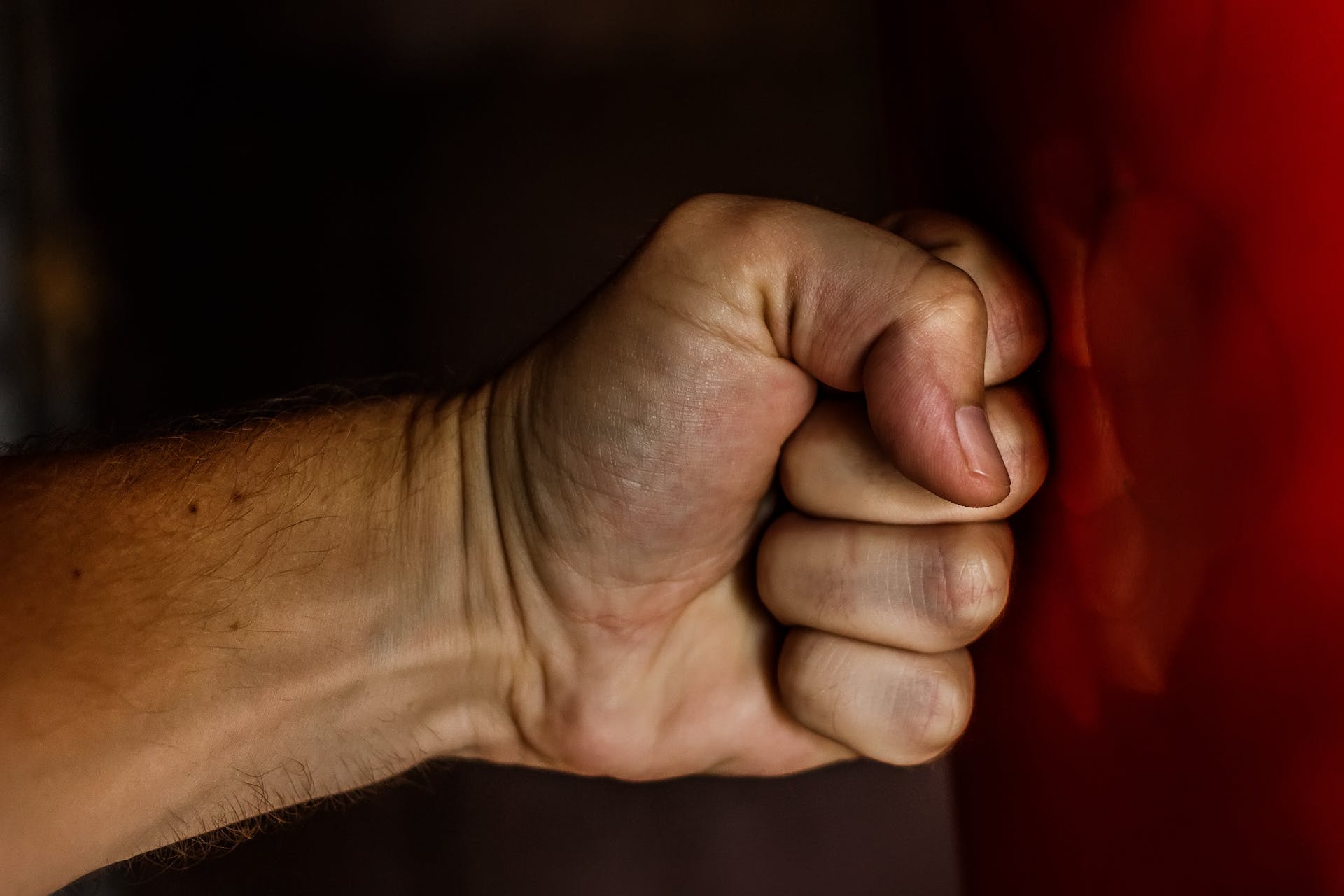 Close-up photo of a human fist punching a red boxing bag