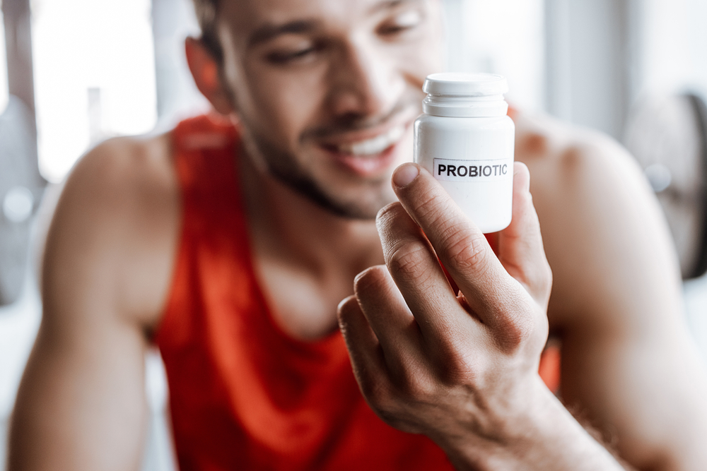 happy sportsman holding bottle with probiotic