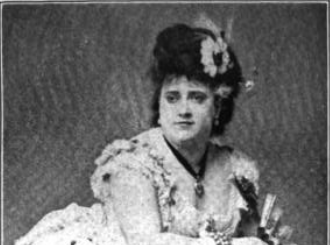 Portrait photo of Josie Mansfield leaning on a chair, wearing white dress