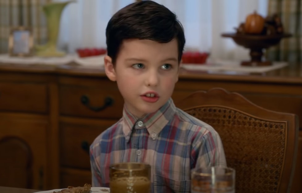 Sheldon in plaid shirt speaking at the table