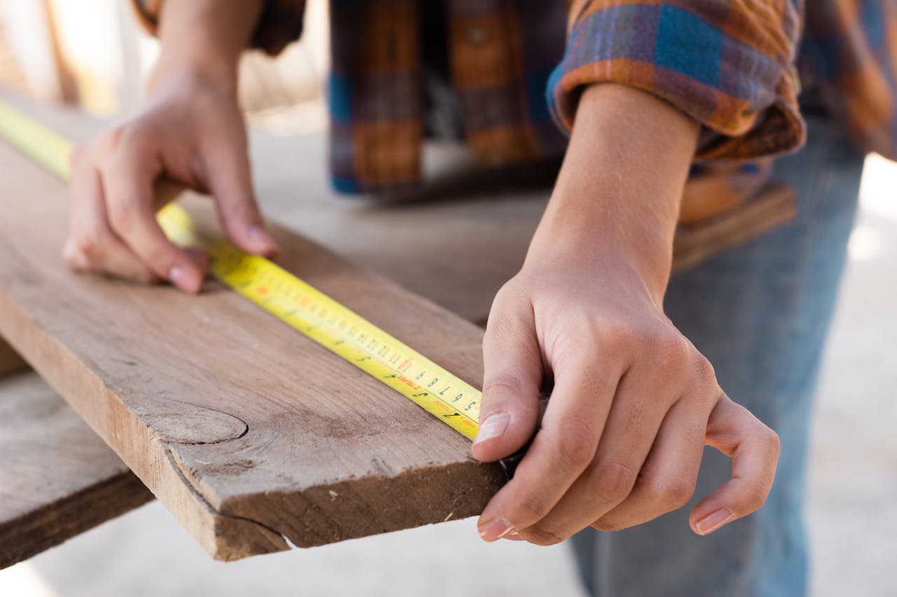 Close up shot of a carpenter measuring a wood plank.