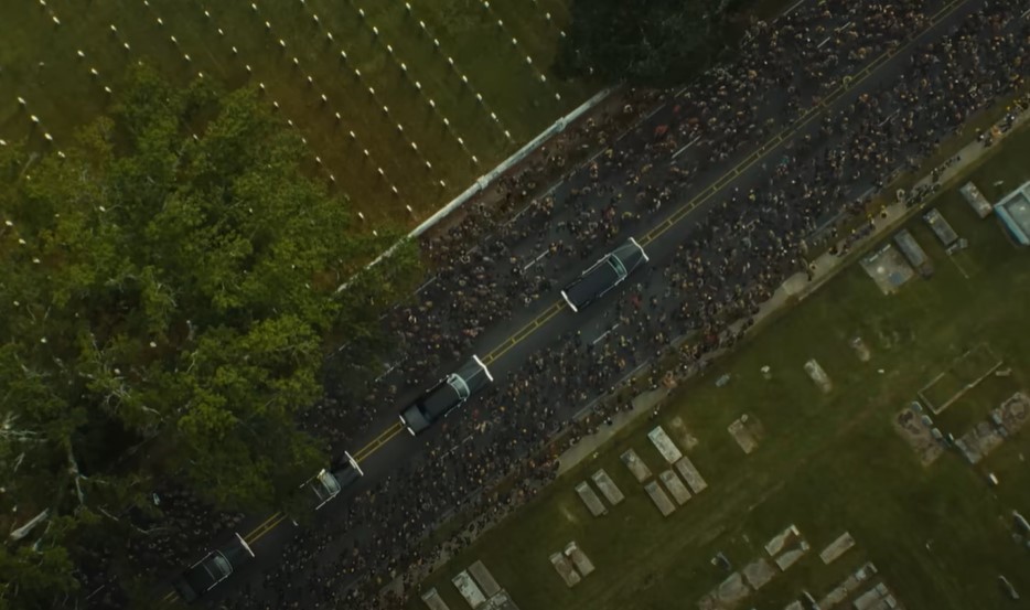 Zac Efron as Kevin Von Erich in The Iron Claw at a funeral