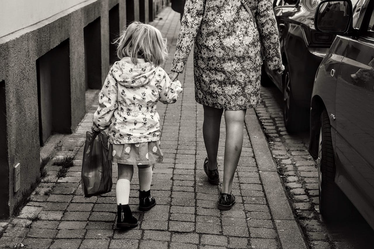 Mother and daughter walking on the sidewalk.