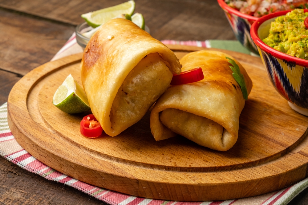 Chimichanga is a traditional Mexican dish, deep-fried tortilla with filling, next to guacamole sauce.