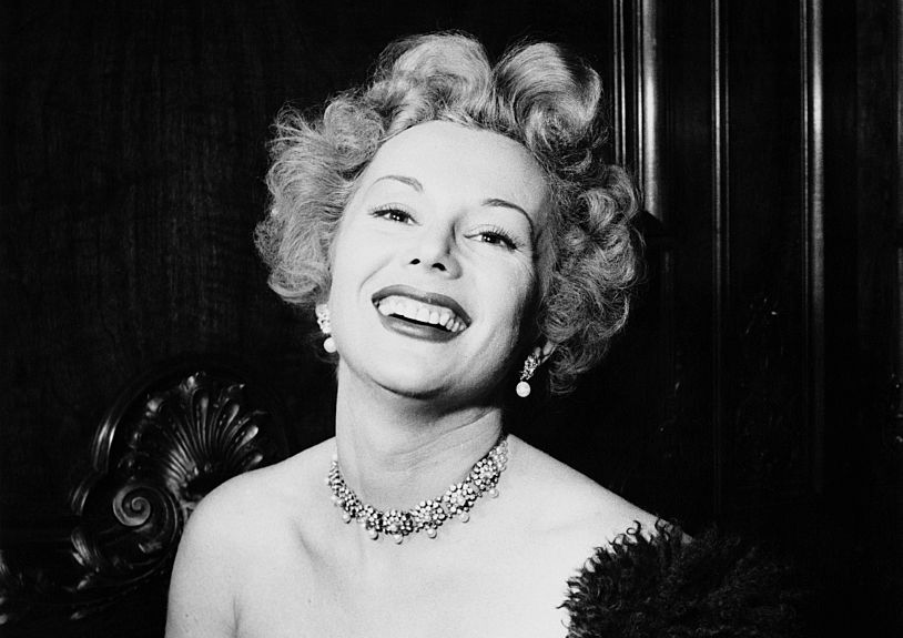 Eva Gabor smiling and wearing jewelry