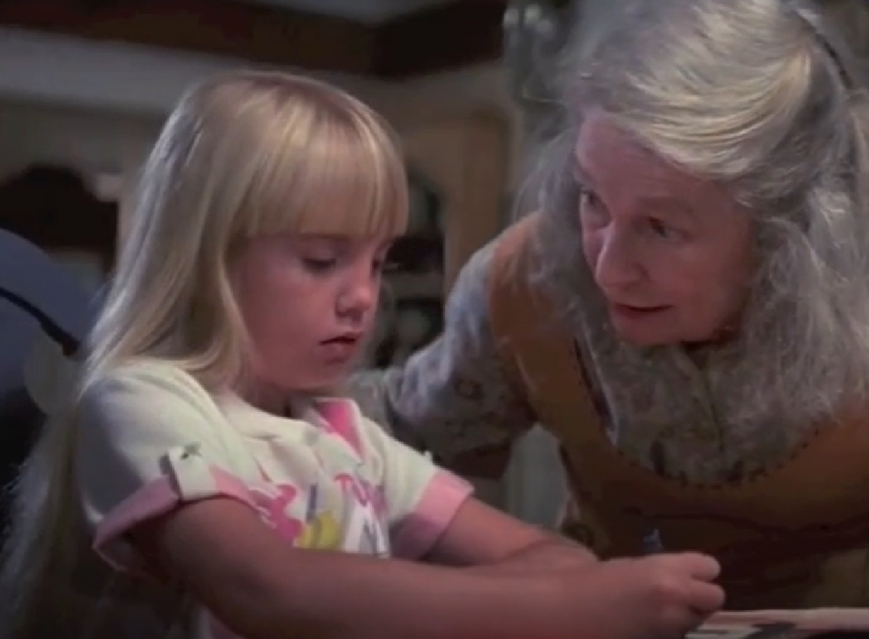 Screenshot of Heather O'Rourke seating on table - from Poltergeist (1982)