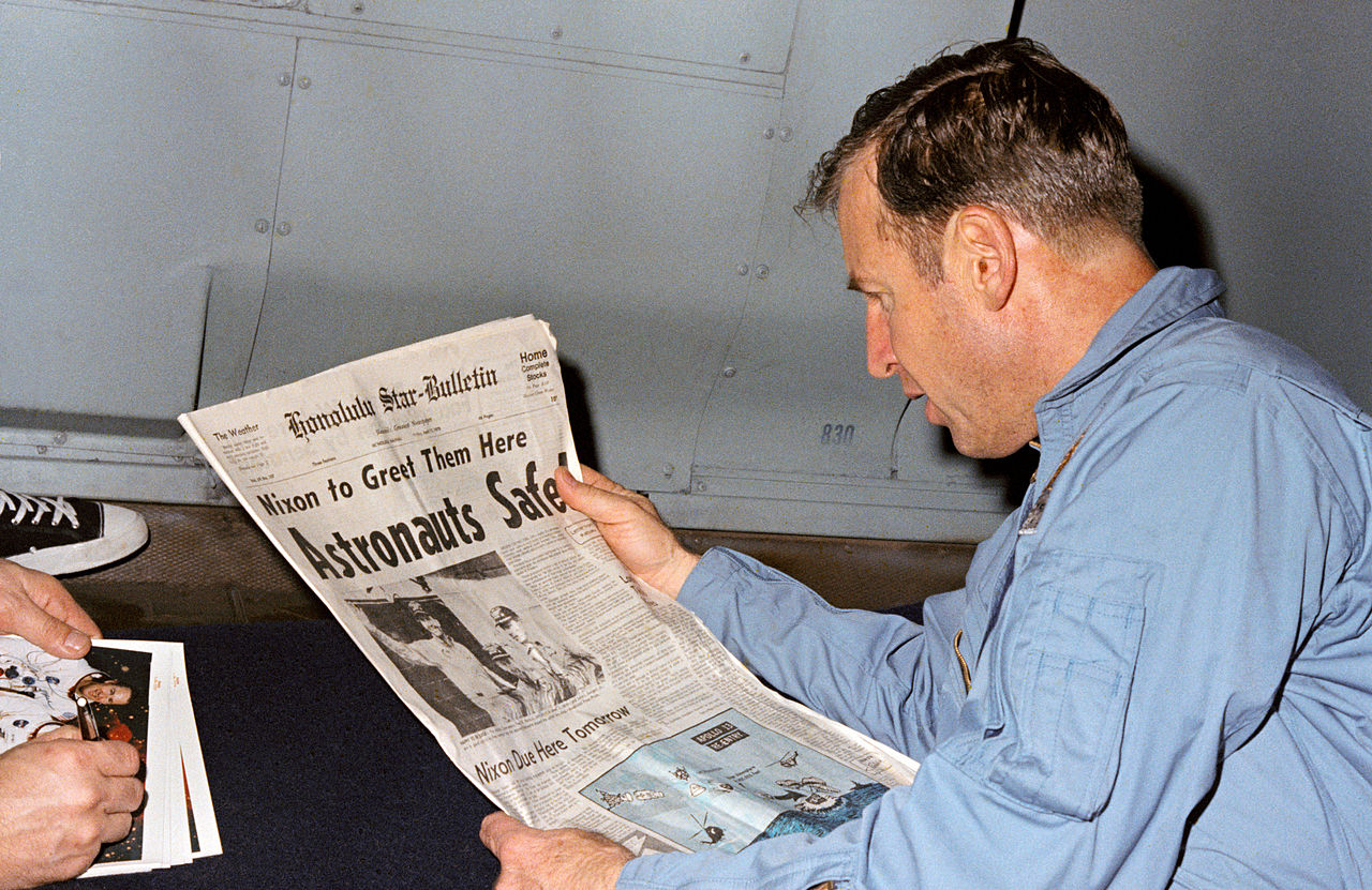 Jim Lovell reading a newspaper