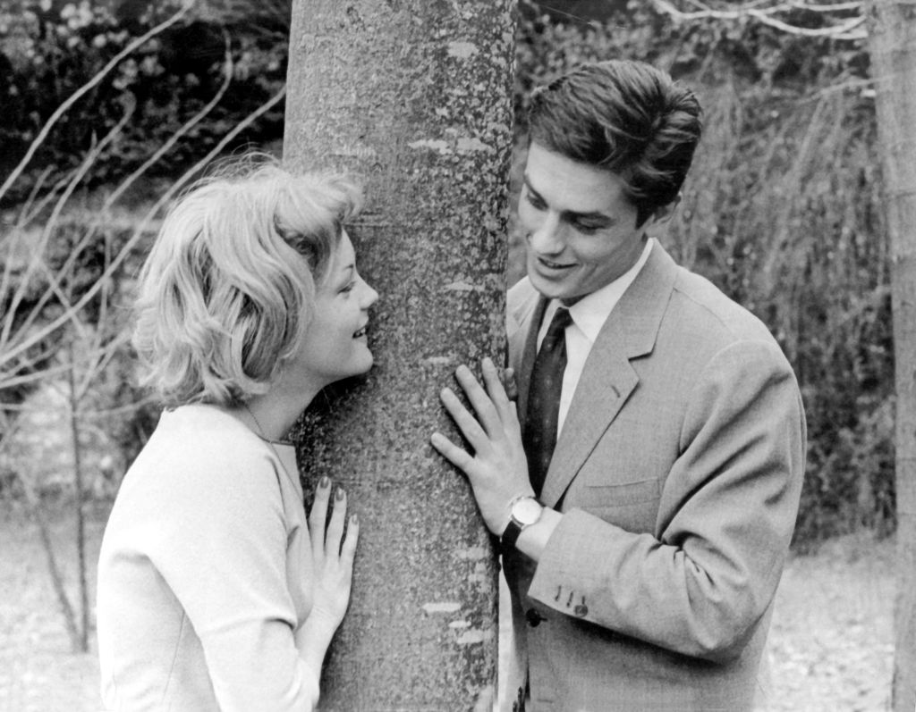Romy Schneider and  Alain Delon standing next to a tree