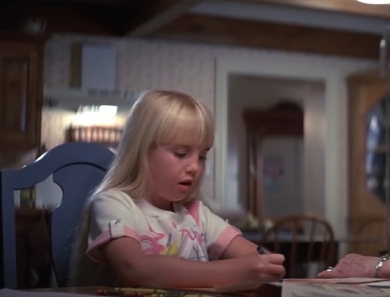 Screenshot of Heather O'Rourke looking seating on the table from - Poltergeist II: The Other Side (1986)