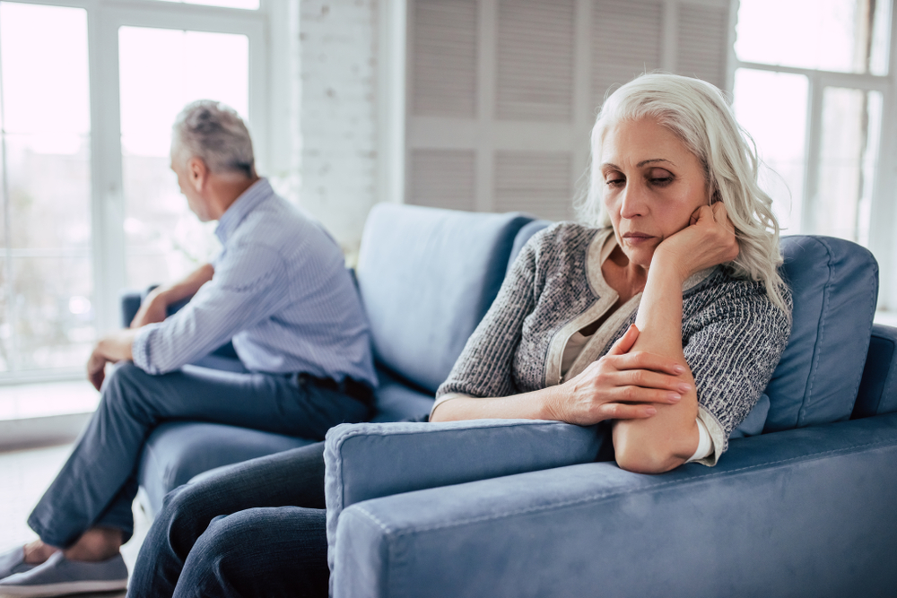 Senior couple sitting on a couch after an argument looking at opposite sides