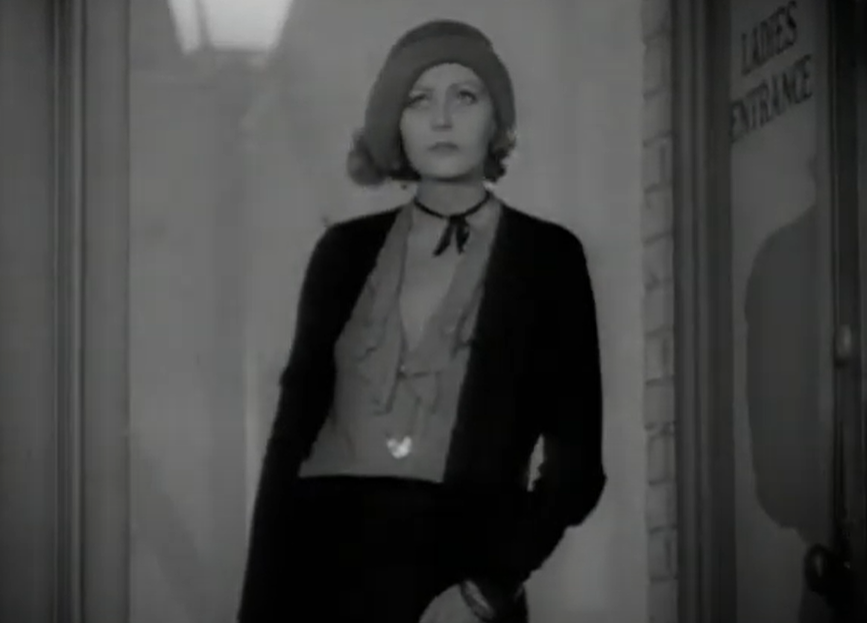 Greta Garbo in movie wearing jacket and a hat