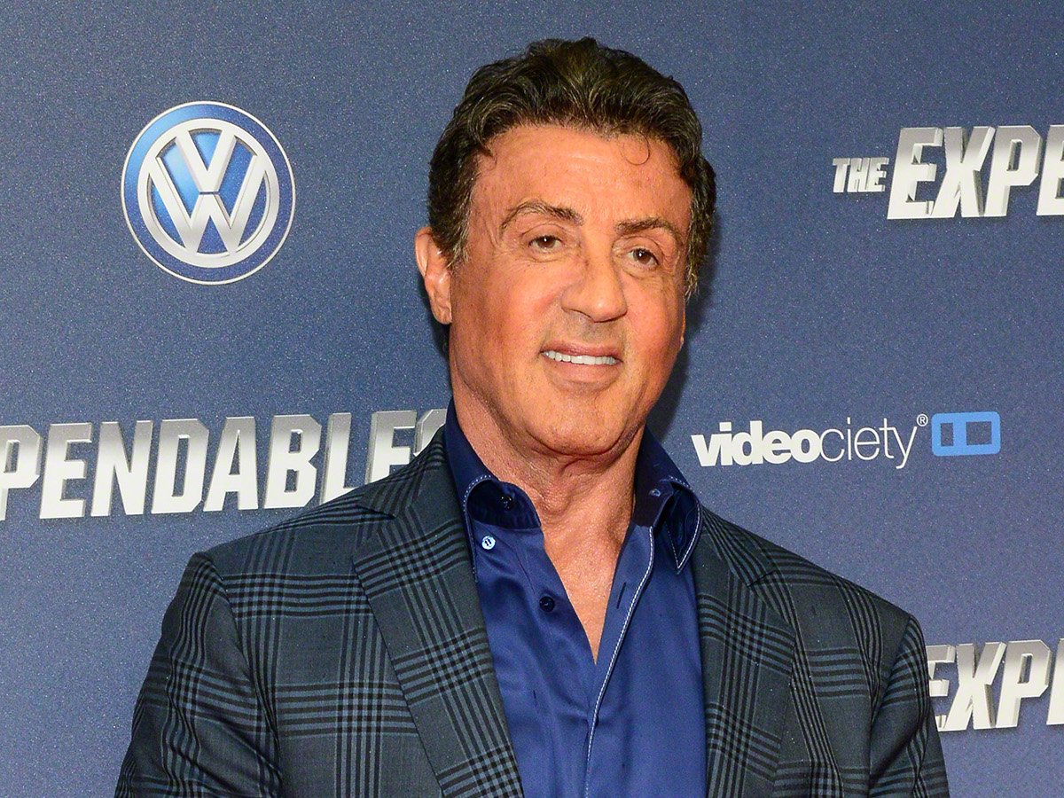 Actor Sylvester Stallone wearing a blue shirt and a grey jacket