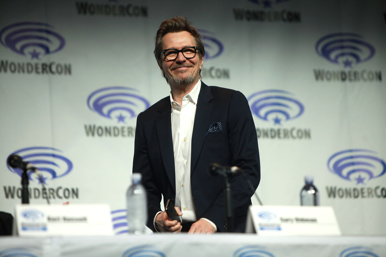 Gary Oldman wearing a white shirt and a black jacket