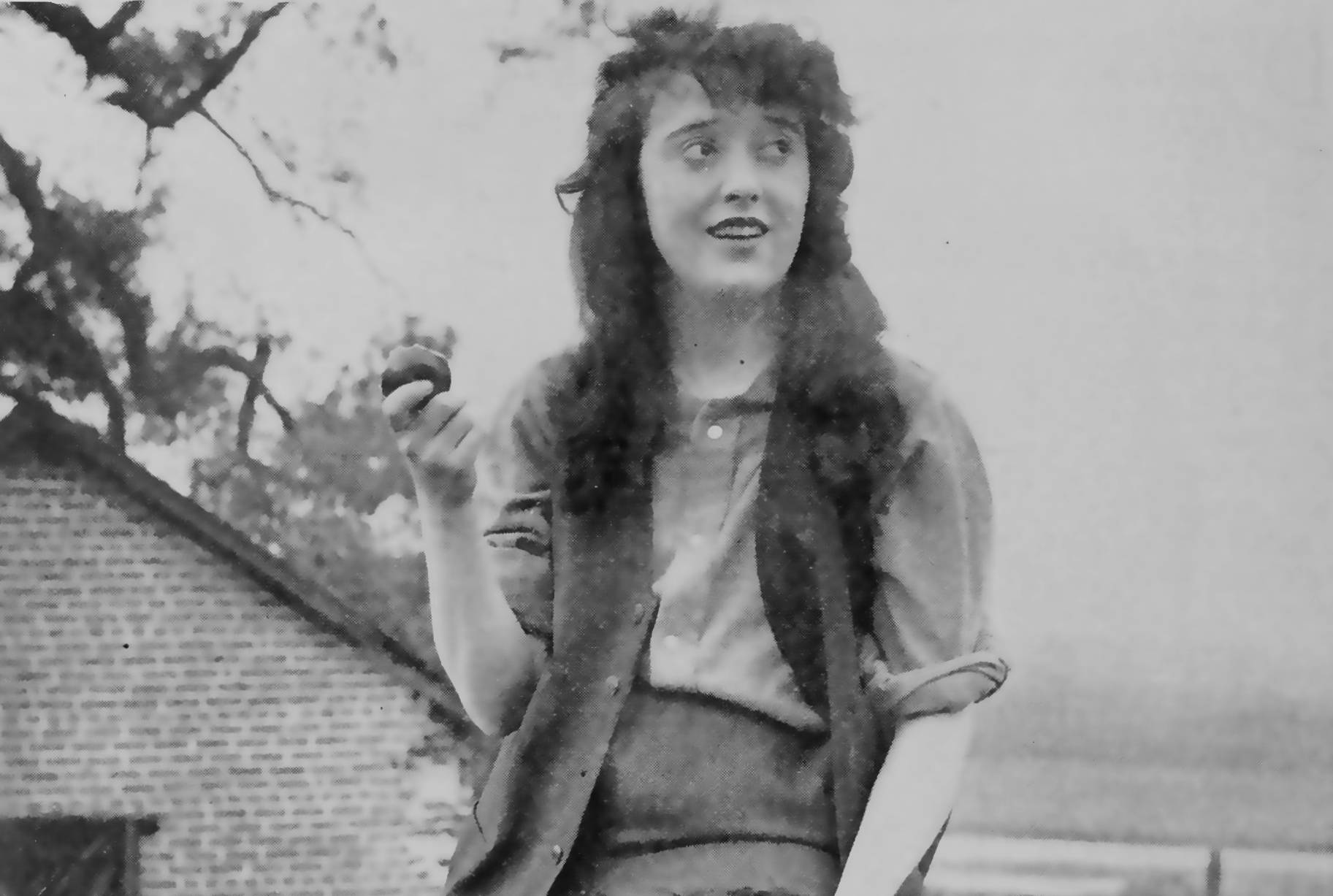 Actress Mabel Normand sitting on a fence post