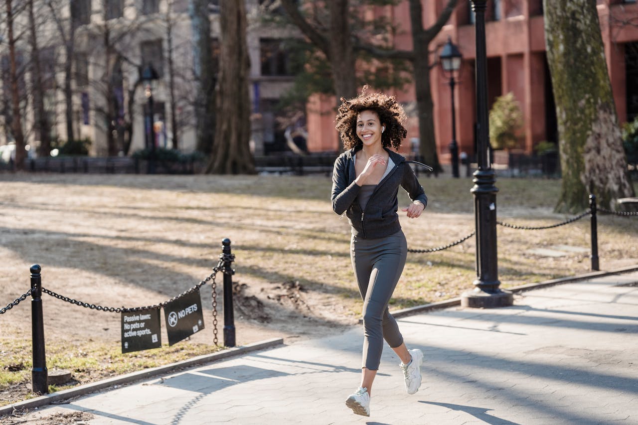 Portrait Photo of Smiling sportswoman running in park
