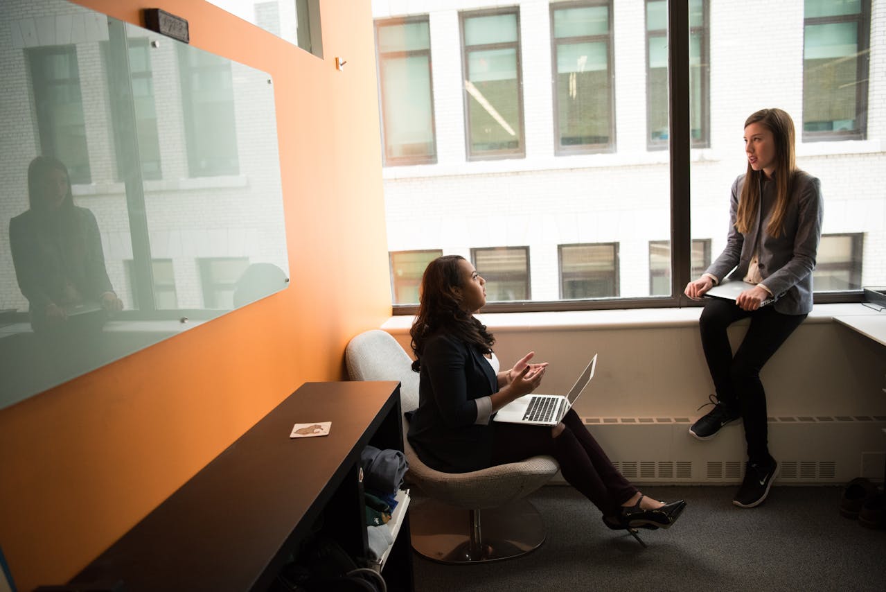 Two Women Sitting in Chair Near Window