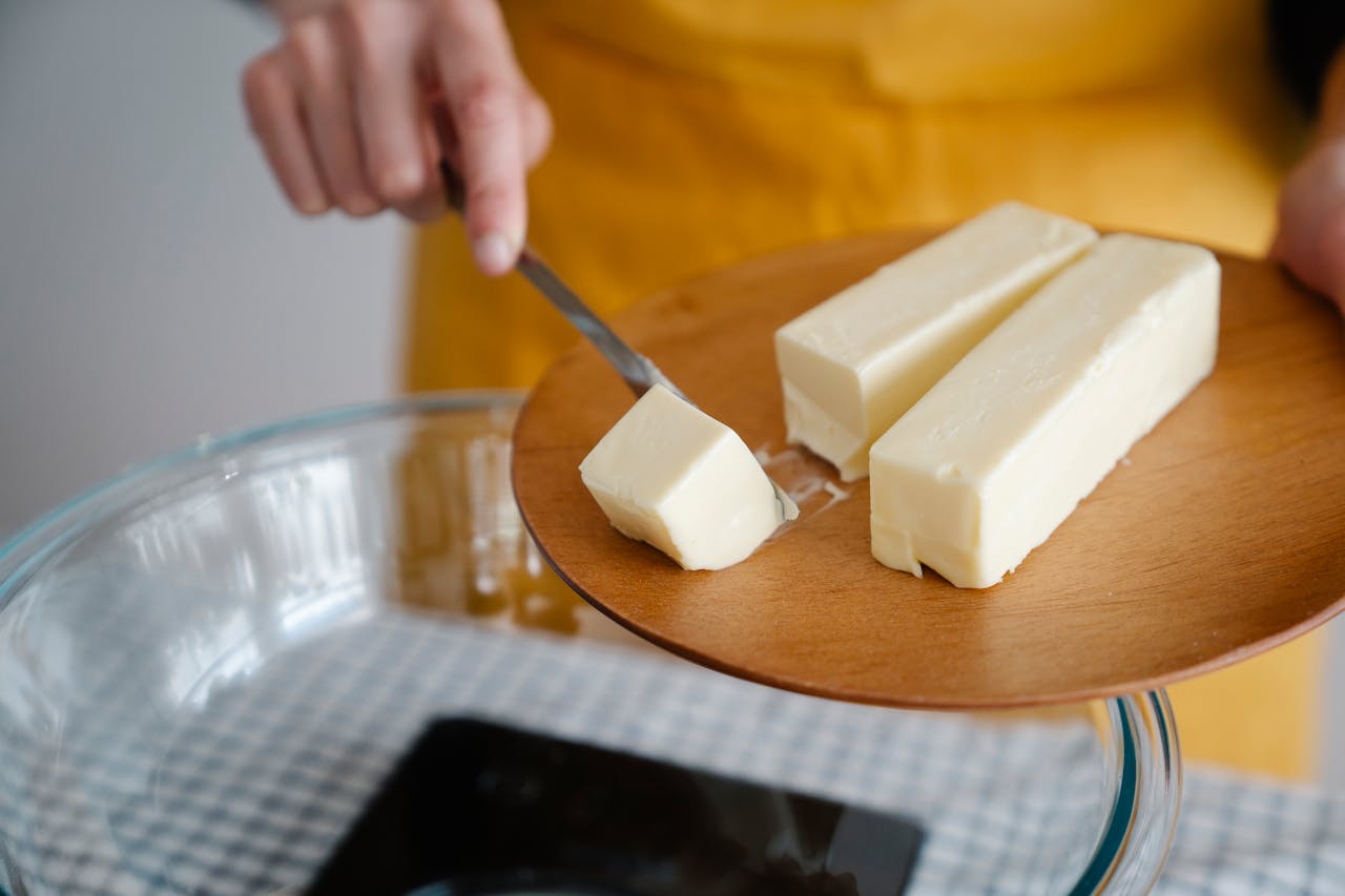 Person cutting Butter on wooden Plate