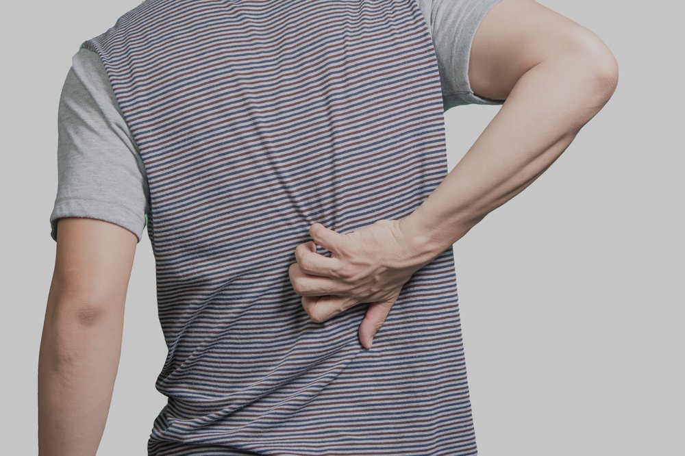 Photo of a person in gray t-shirt scratching his back