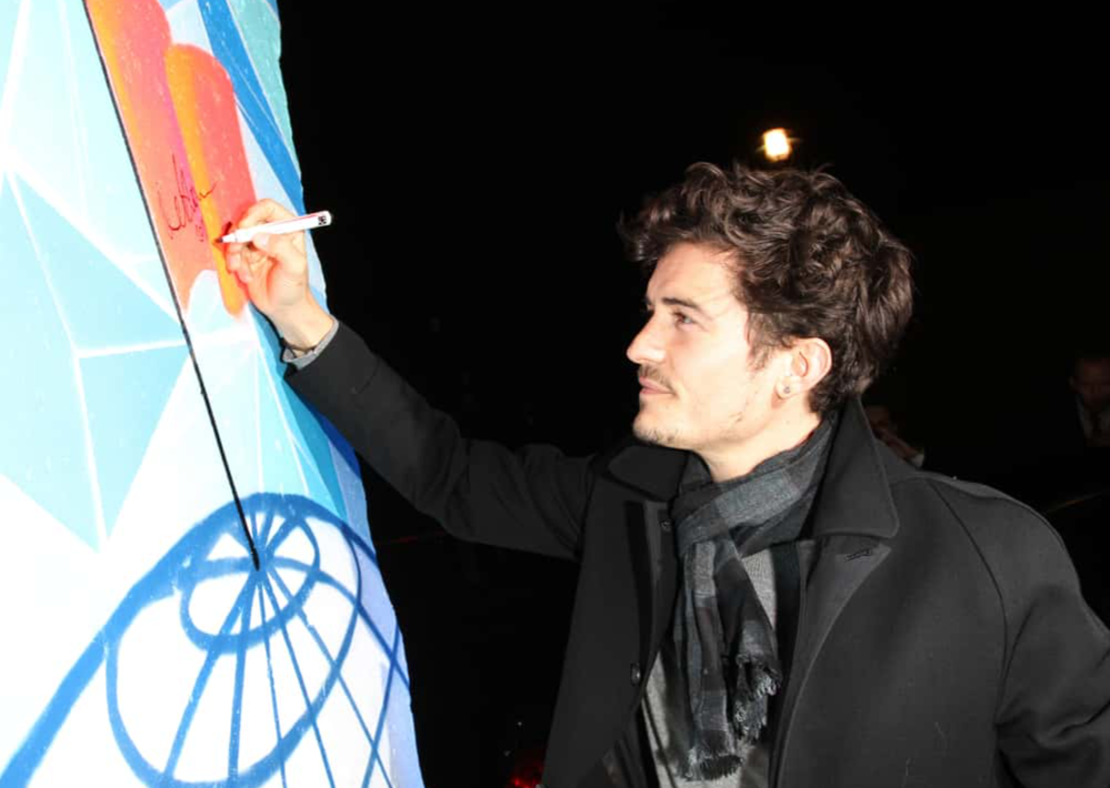 Orlando Bloom signing a piece of the former Berlin Wall