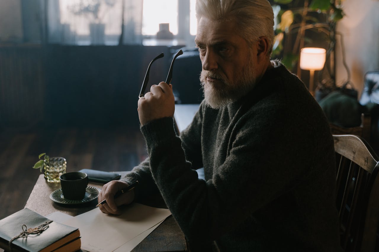 An Elderly Man in Gray Sweater Holding an Eyeglasses