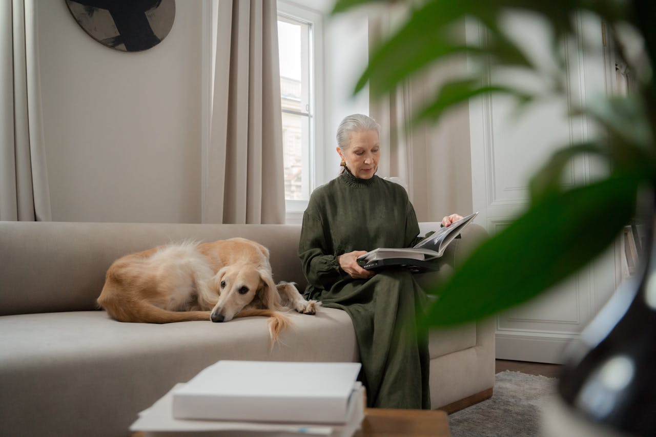 Elderly Woman Sitting on Sofa Next to a Dog