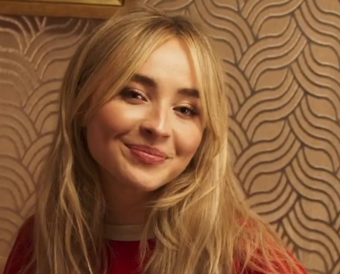 Portrait Photo of Sabrina Carpenter in red outfit, smiling