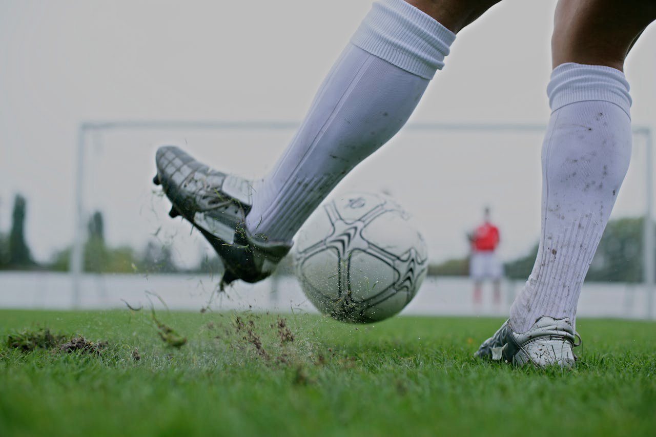 Legs of a Soccer Player Kicking the Ball