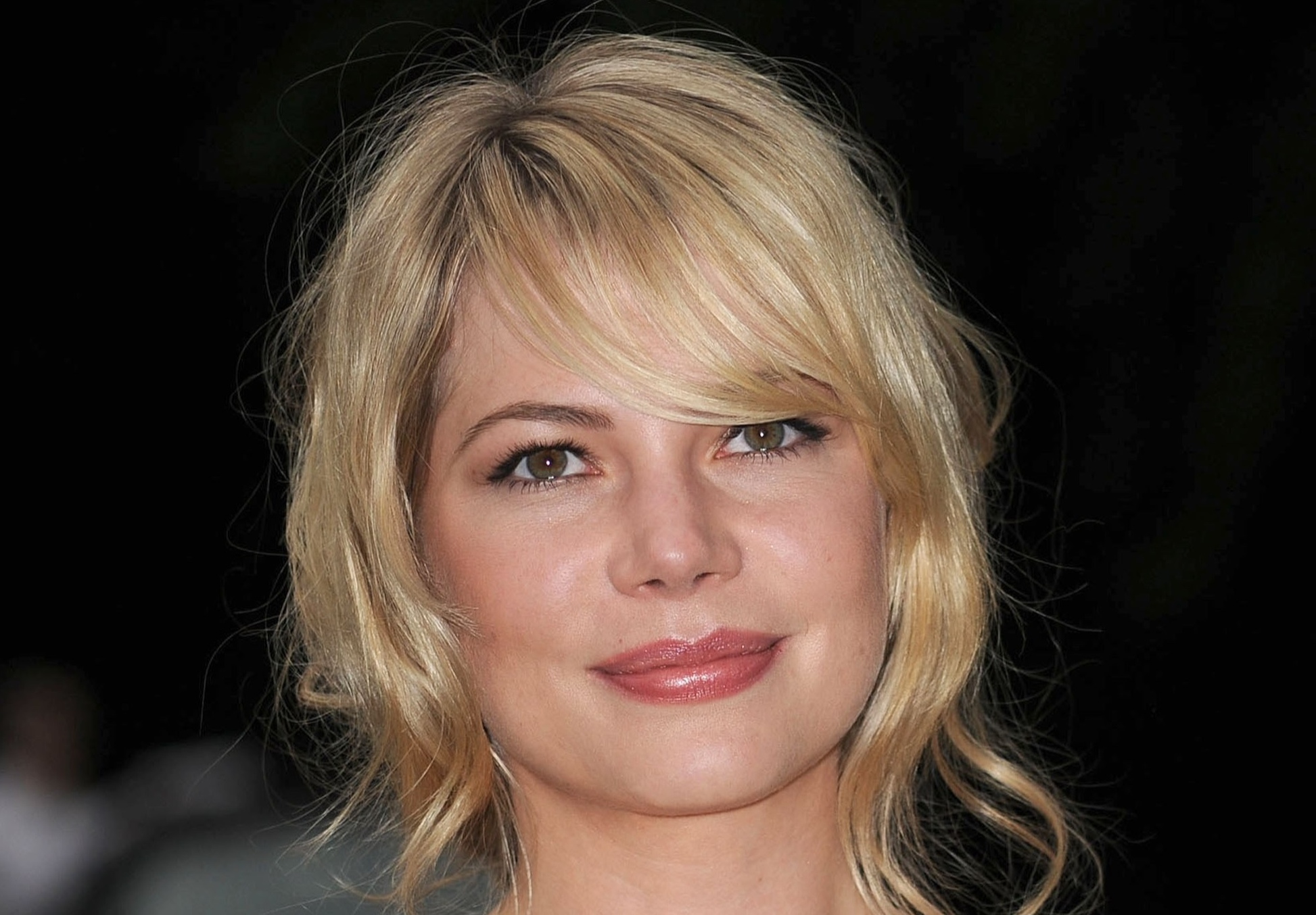 Photo of Michelle Williams in white and gold dress smiling at camera - 2009