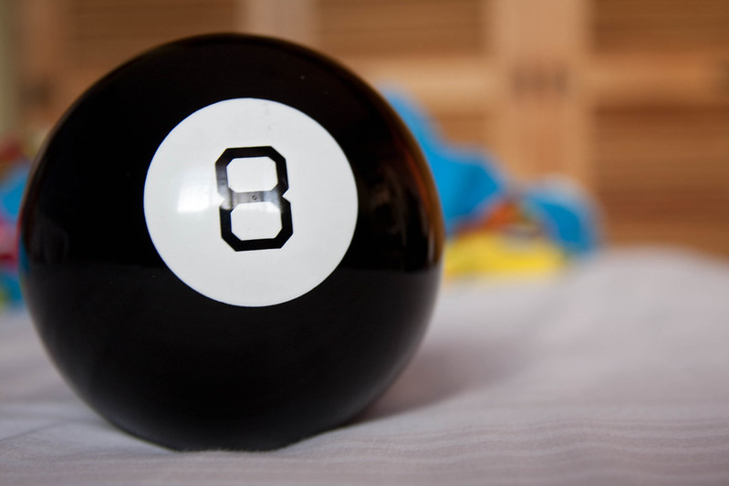 The image shows a Magic 8-Ball on a white surface