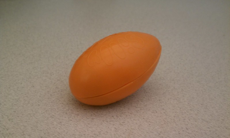 The image shows an orange, oval-shaped Silly Putty on Blurred Background.