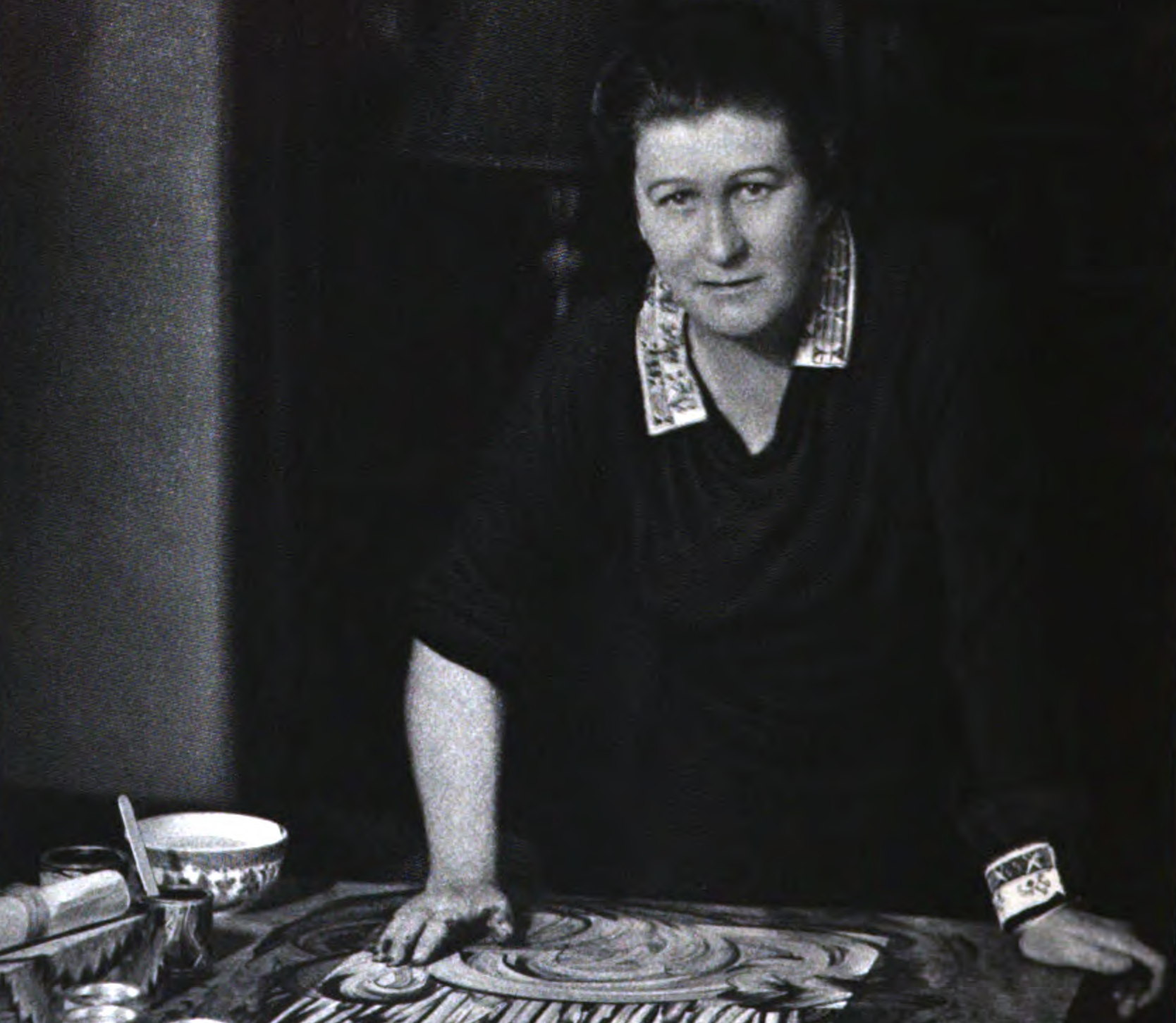 Grayscale Portrait Photo of Ruth Faison Shaw standing by a finger painting