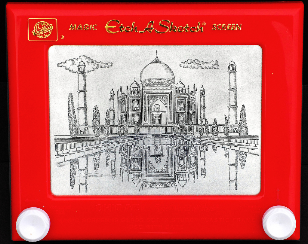 The image shows a classic red Etch A Sketch toy wit Taj Mahal on screen