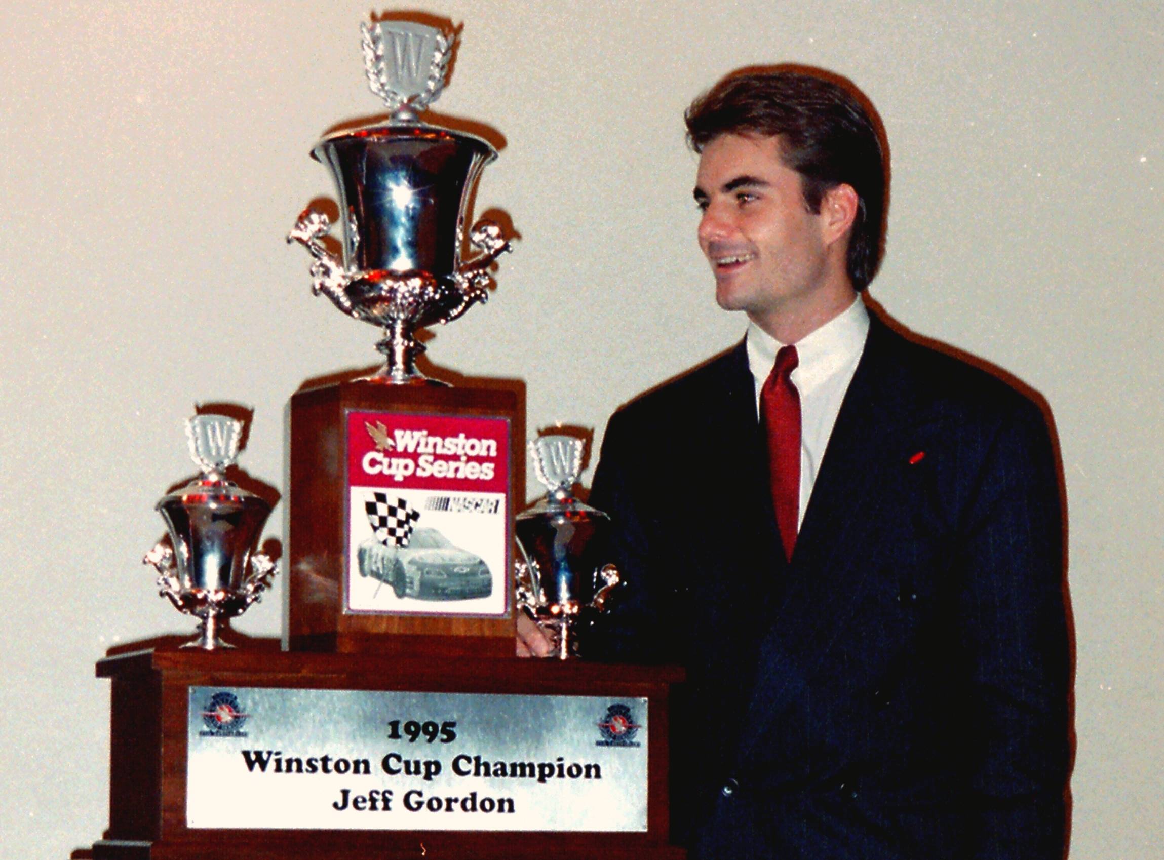 Jeff Gordon in suit next to awards