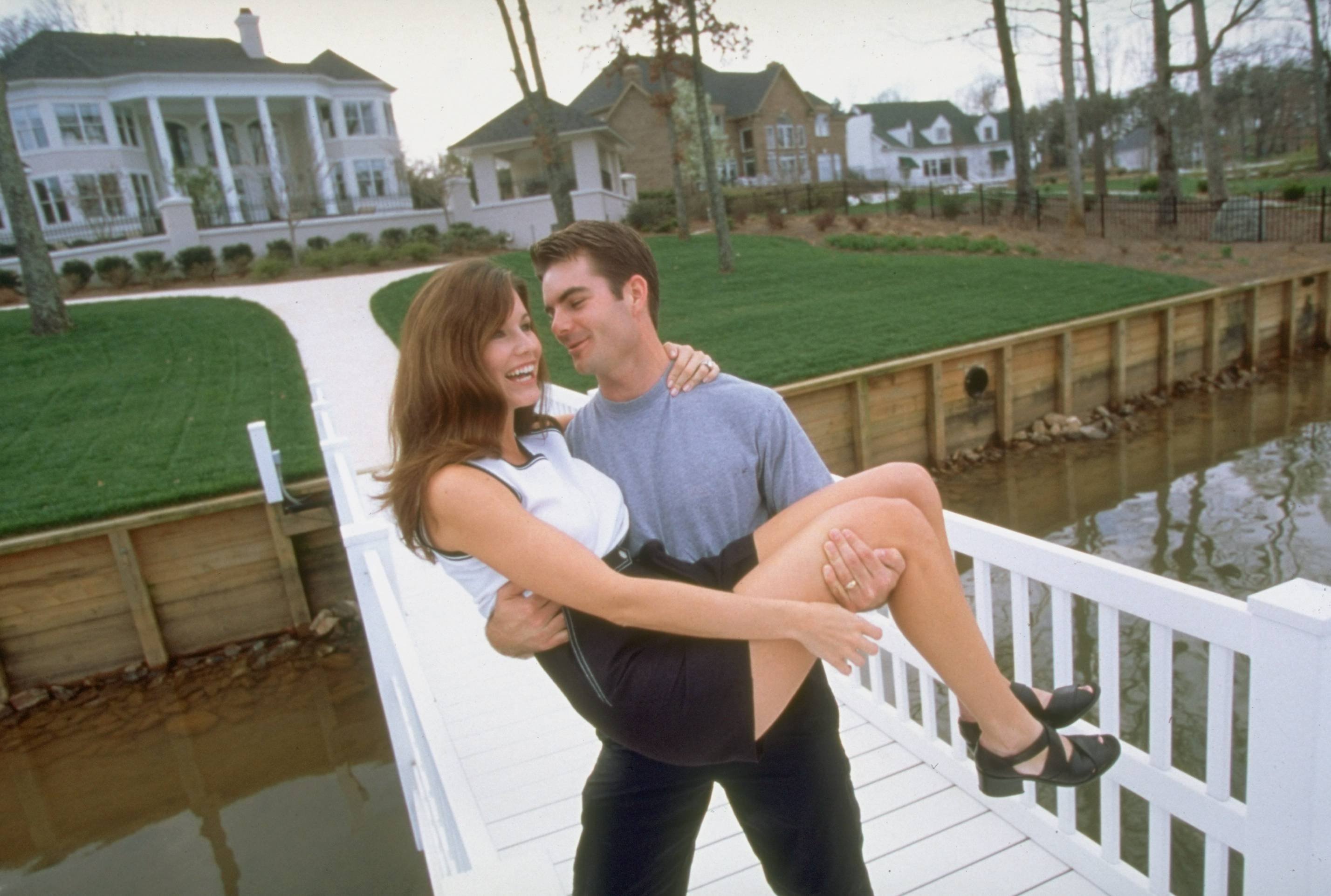 Race car Driver Jeff Gordon carrying wife Brooke on a dock