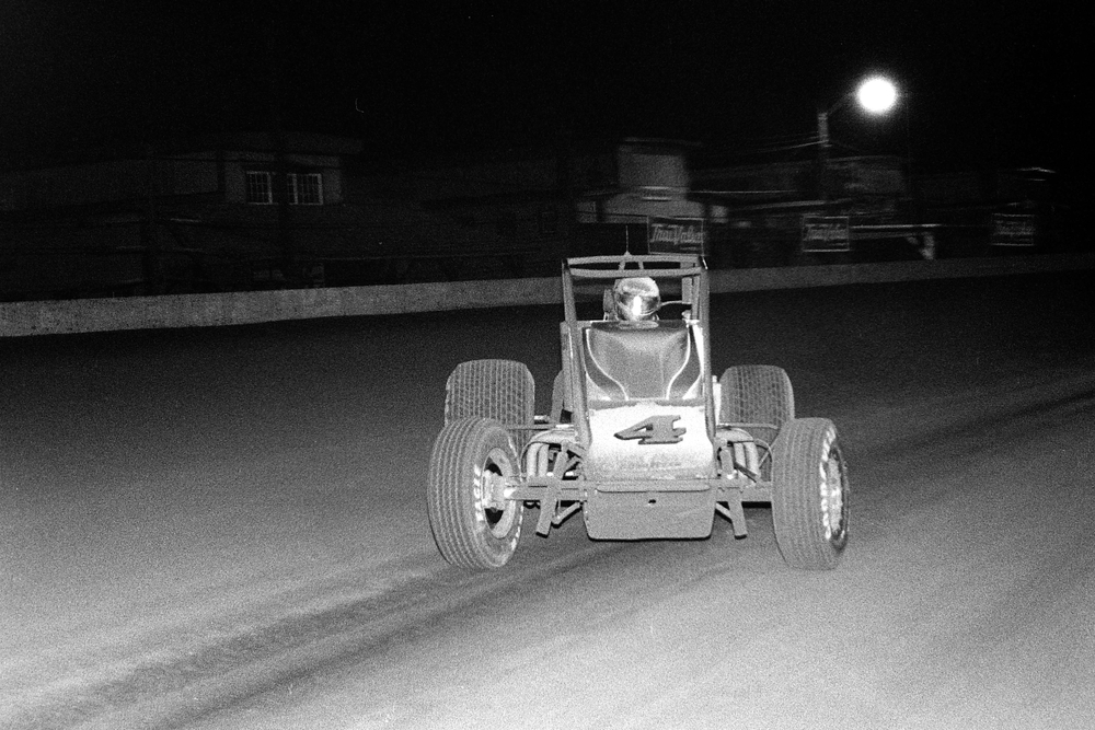 A grainy, old-school black-and-white photo of NASCAR legend Jeff Gordon competing in a USAC Silver Crown race