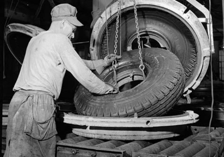 Workman removes a synthetic rubber tire from the vulcanizing oven