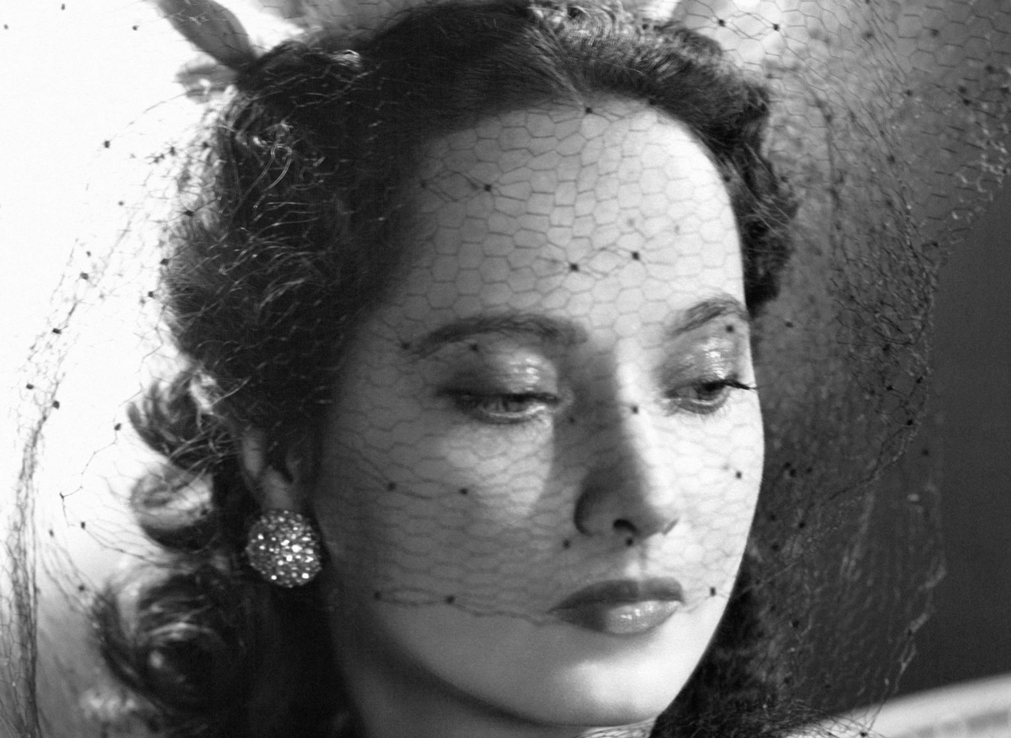 British actress Merle Oberon wears an elegant hat with a veil